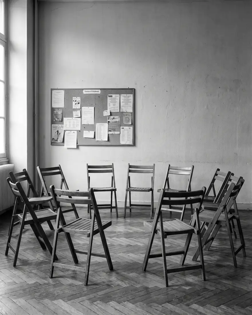 Des chaises pliantes disposées en cercle dans une salle d’association.